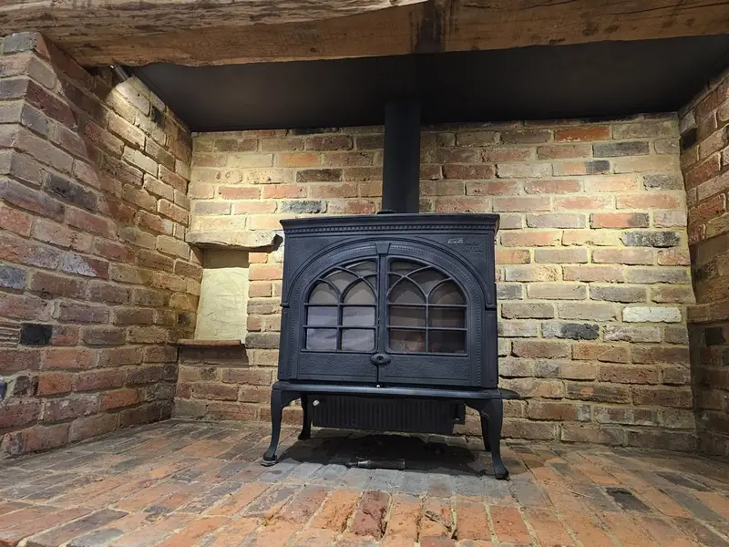 A wood burner fitted in a brick fireplace with a brick hearth